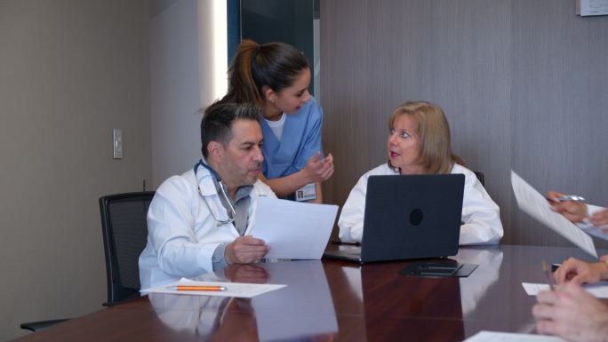 一组医生和护士正在讨论一个病例，同时在笔记本电脑上查看患者的病历表