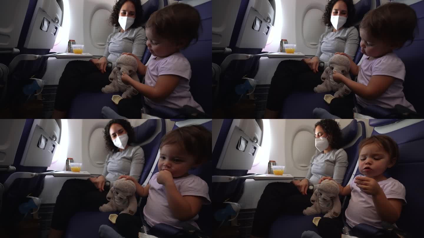 孕妇和蹒跚学步的女儿在飞机上吃零食