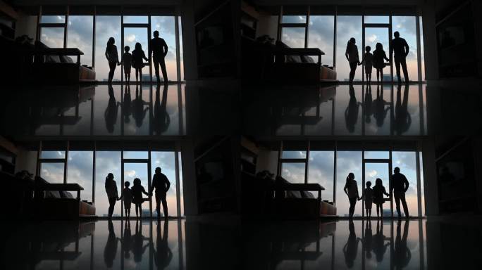 剪影后视图：吉隆坡市，一个亚裔华人家庭带着两个孩子透过窗户观看美丽的日落