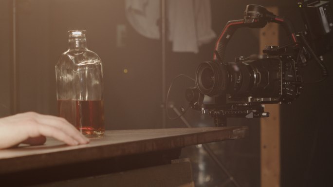 视频的后台，一个醉汉和一瓶威士忌放在桌子上