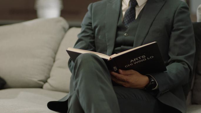 商务男士坐沙发上看书看手表