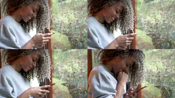 一个非洲头发的拉丁女人在她的客厅里用她的手机