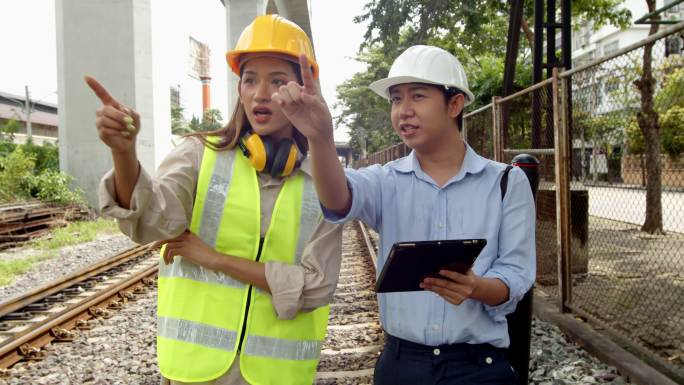 两名男工程师和一名女检查员检查火车轨道的状态。工程铁路