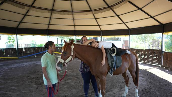 孤独症女孩在私人中心接受马匹治疗。