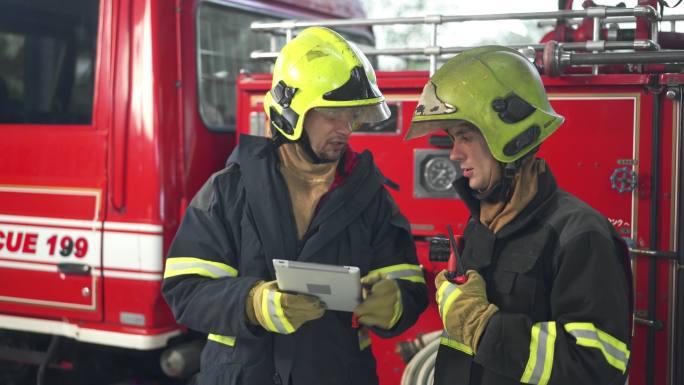 两名男性消防员在消防站使用数字平板电脑