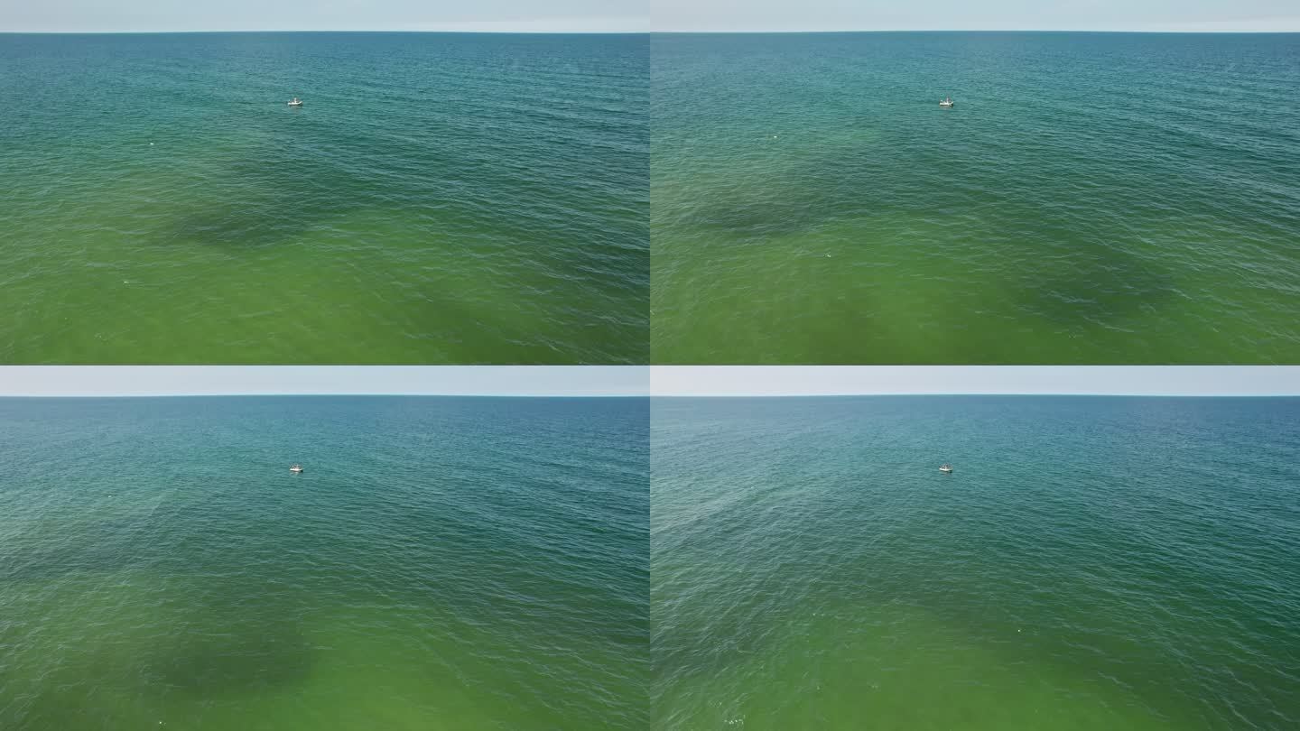 一个渔夫在渔船上捕鱼。在海上钓鱼。无人机的射击。从远处的圆形摄像机移动。地平线视图。