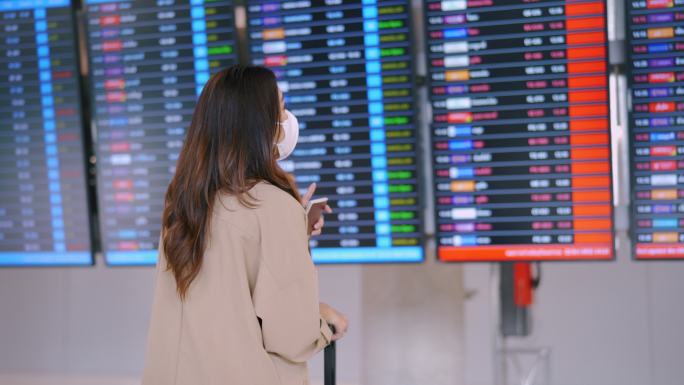 旅客戴着口罩在机场查看航班时刻表。