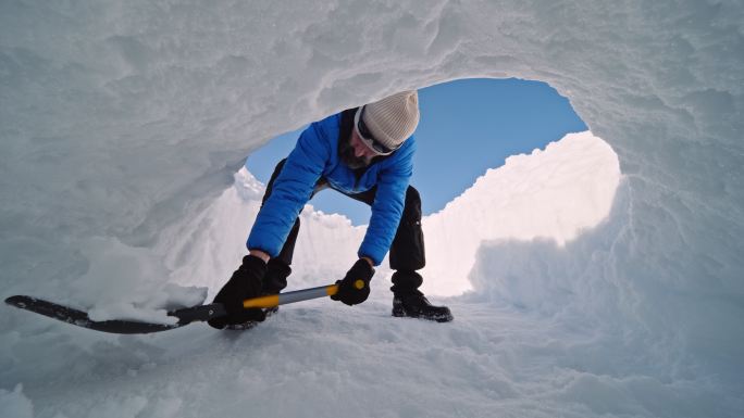 成熟的游客在雪地里为冬季露营挖洞。在自然界中是孤独的。