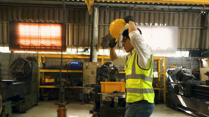 工程师们正在为工业工人使用机器。戴着安全帽和反光背心的亚洲男女工人在工厂工作。侧视慢动作场景：工厂里