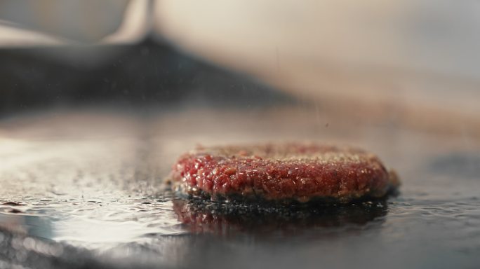 一个汉堡馅饼在烤架上调味的4k视频片段