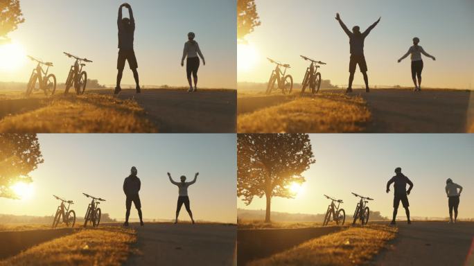 太阳升起时，两个山地自行车手在乡村做伸展运动