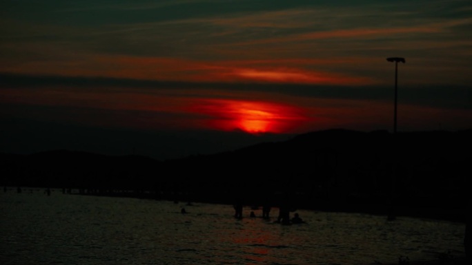 夕阳 火红的太阳 落日余晖 海边的人群