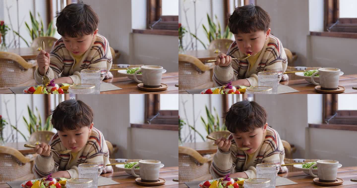 小男孩正在吃沙拉童年悠闲随意