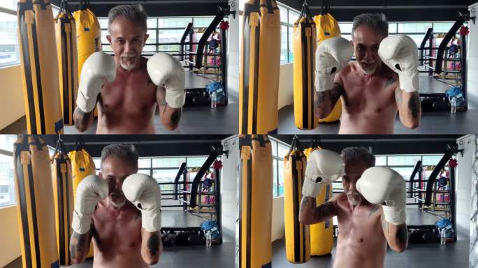 太极拳亚洲中国高级男子泰拳拳击手在健身房里对着镜头打拳