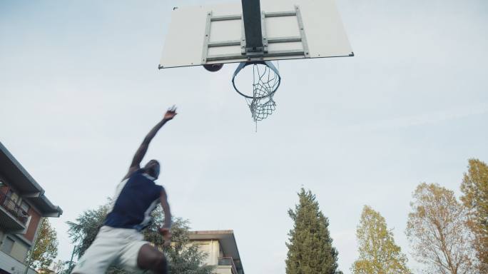 一名年轻男子在篮球场上进球的低角度视图