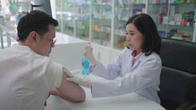 自信的亚洲女药剂师准备给年轻人注射疟疾、破伤风、伤寒和肝炎疫苗。