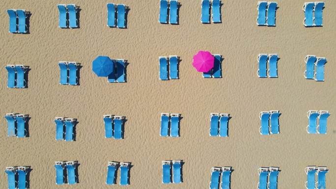 空沙滩上的空沙滩伞，4K分辨率，躺椅和海景的鸟瞰图，日光躺椅伞，沙滩上的日光躺椅和雨伞，空沙滩和空日