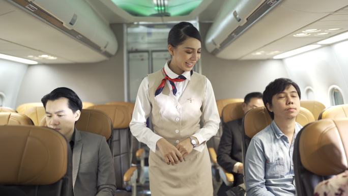 4K微笑的空中小姐穿着制服在飞机上检查乘客