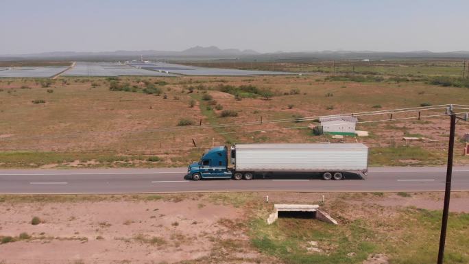 一辆长途半卡车在墨西哥高速公路上疾驰，经过一个太阳能发电站
