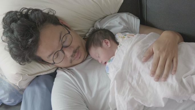 4k快乐疲惫的亚洲父亲和儿子早上睡在沙发上。