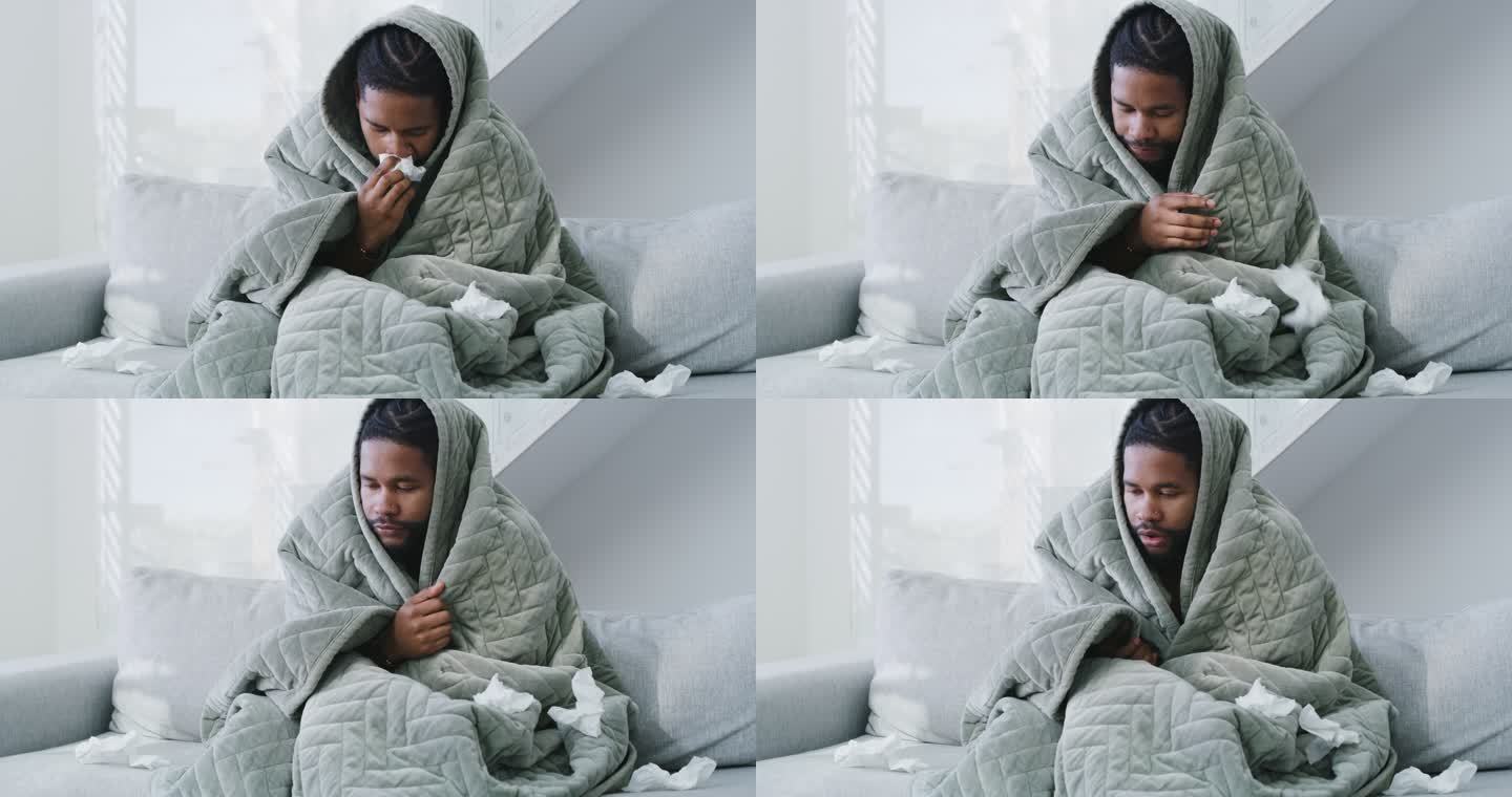 一个年轻人在家里得了流感，躺在床上。感觉不舒服的人，用毯子盖住，用纸巾擤鼻涕
