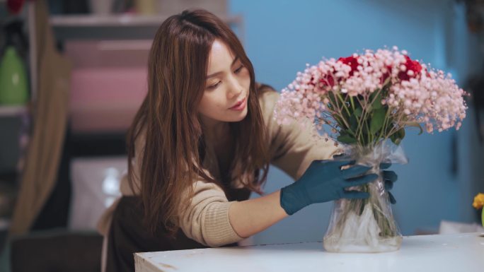 特写亚裔中国女花商，小企业主，在花店包装和布置花束。经营小企业的日常工作