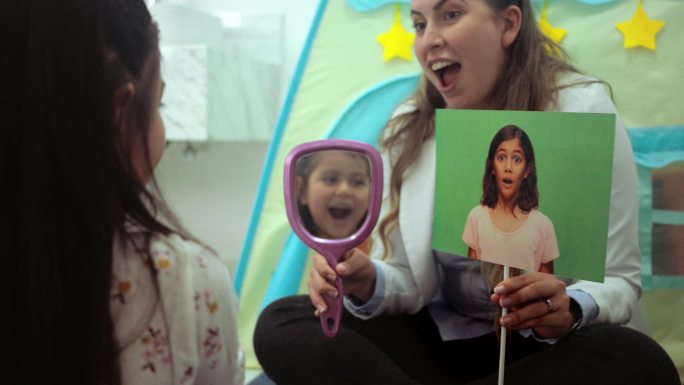 女心理学家在治疗中为小女孩拿镜子，同时展示和想象