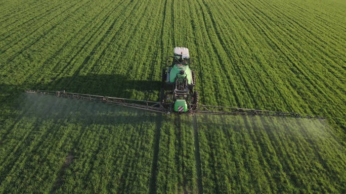 拖拉机为绿色小麦种植农田施肥的鸟瞰图。