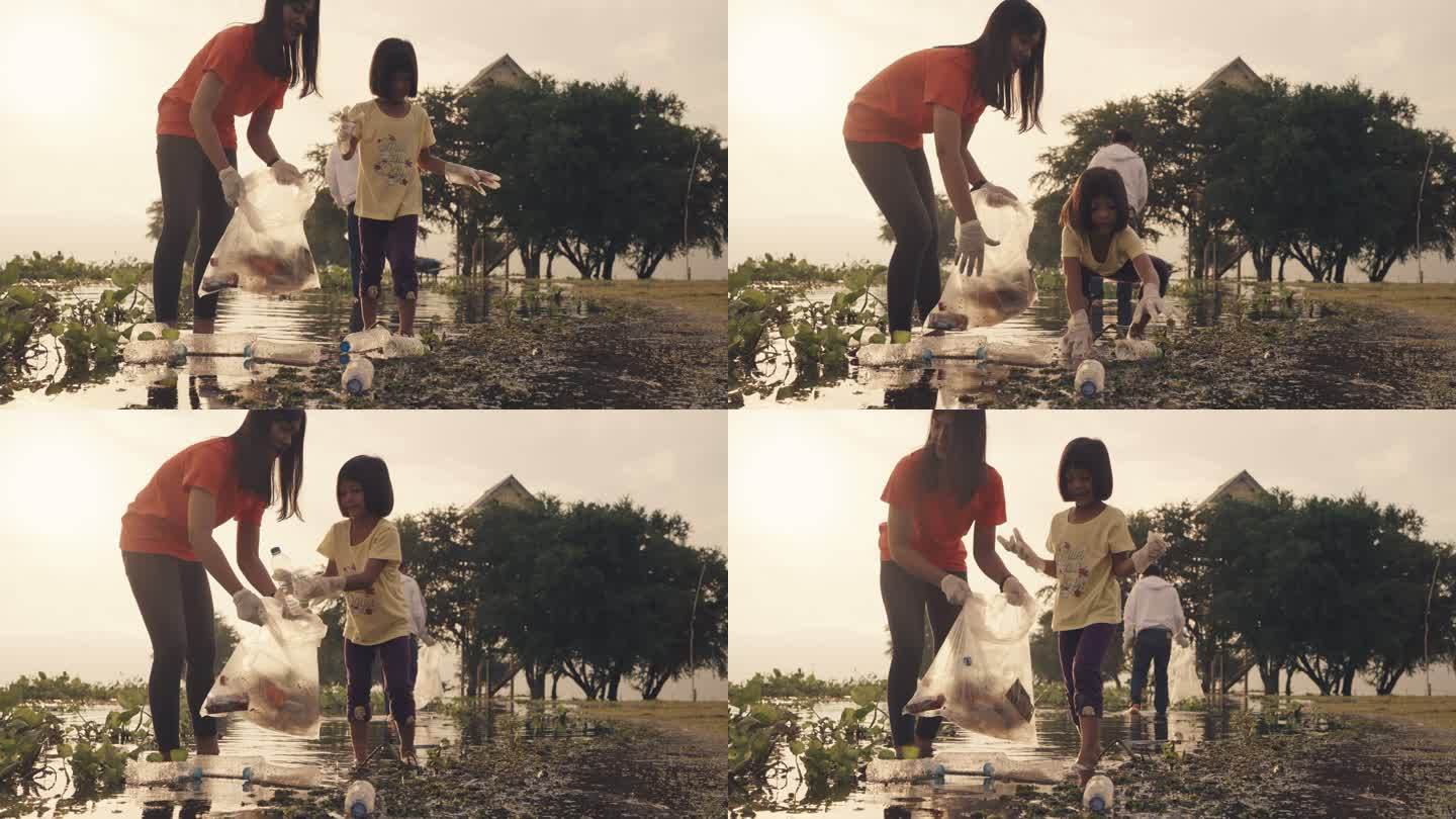 亚洲志愿者家庭晚上在河边收集塑料瓶和水葫芦。