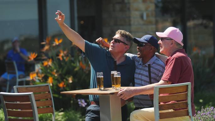 男性高尔夫球手朋友用照相手机自拍，喝啤酒