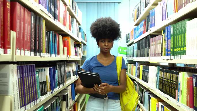 一位年轻女子在图书馆里拿着一些书的肖像