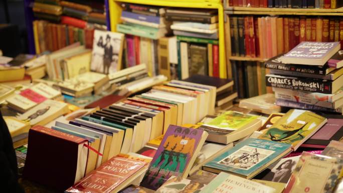 一个年轻人在二手书店里看旧书，在波托贝罗路跳蚤市场的一个市场摊位上出售复古书籍