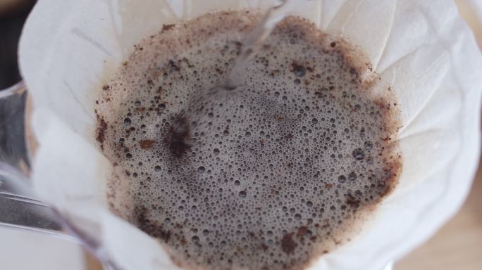 手滴咖啡，咖啡师用过滤器将水倒在咖啡地上，慢动作