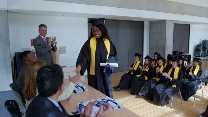 快乐的非洲裔美国女毕业生，收到毕业证书并和老师和院长握手
