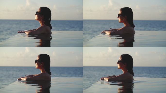 女人在游泳池里放松，看日落