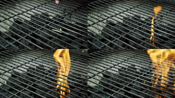 一个高加索人的手把点燃的木柴扔到户外烧烤架上，点燃木炭块准备烧烤