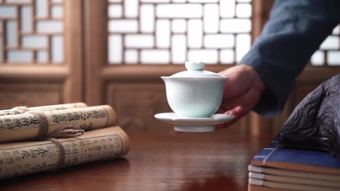 把沏好的茶碗放到古代文人书房书桌上