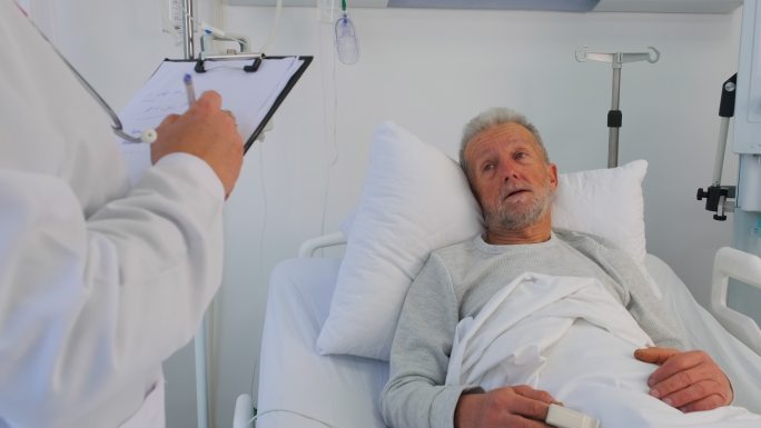 医院病房：友好的护士与卧床休息的老年男性患者交谈，检查她的生命体征，记录信息。