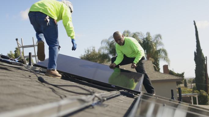 在加州住宅屋顶安装太阳能电池板的工人团队