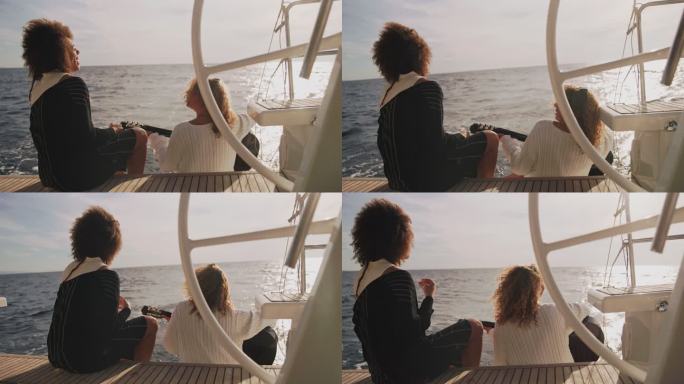 斯洛·莫：两个年轻女子在日落时在船上弹着吉他唱歌