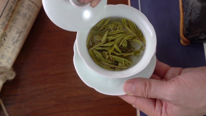 拿起茶碗盖子划拨茶叶绿茶喝茶