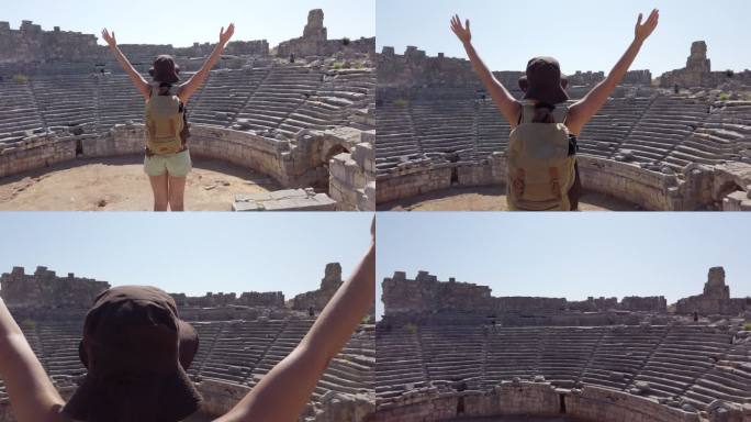 土耳其安塔利亚，一名女摄影师在桑索斯圆形剧场古城的古代遗址中张开双臂