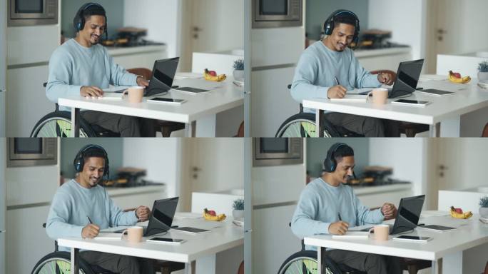 亚洲印度残疾人坐在餐厅的轮椅上，用笔记本电脑进行视频通话