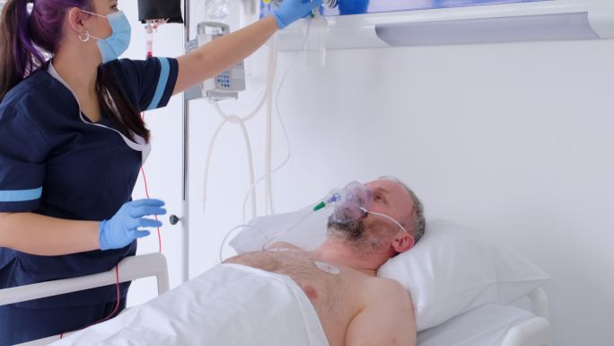 这名男子戴着氧气面罩躺在医院的床上，恢复了知觉