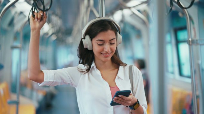 一个女人在地铁里握着扶手听音乐