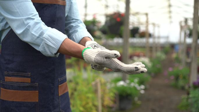 在花园中心工作时戴上防护手套的一名面目全非的男子的特写镜头