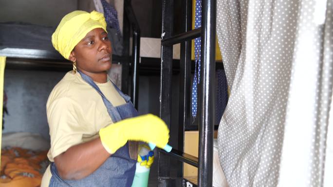 4K视频，一名非洲裔女性在宿舍房间使用清洁海绵和酒精消毒剂喷雾进行清洁