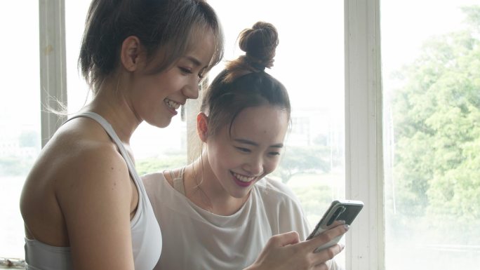 两个亚洲女孩使用智能手机笑