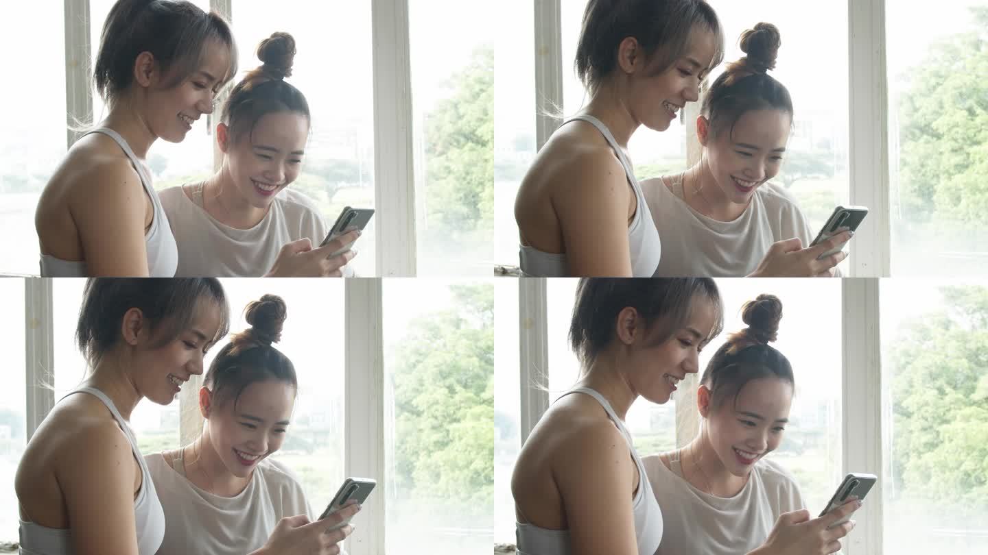 两个亚洲女孩使用智能手机笑