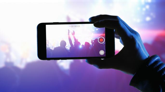 一位女士在音乐会上使用智能手机录制活动视频